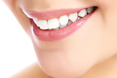 A close-up image of a person s smiling face with noticeable teeth whitening, highlighting the cosmetic dental service being advertised.