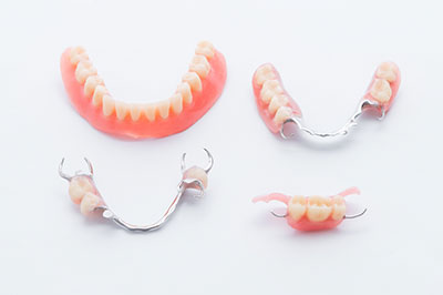 A set of dentures with a toothbrush, displayed on a white background.