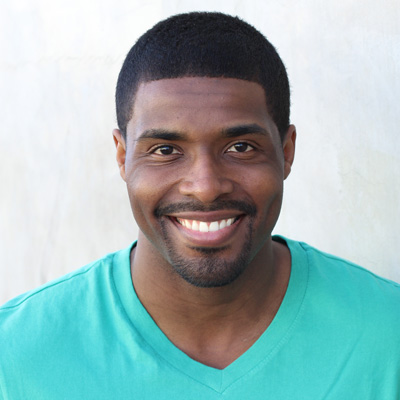 An elderly couple sharing a warm smile, seated closely together outdoors.