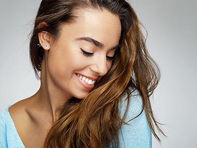 The image features a young woman with long hair, smiling and looking downwards.